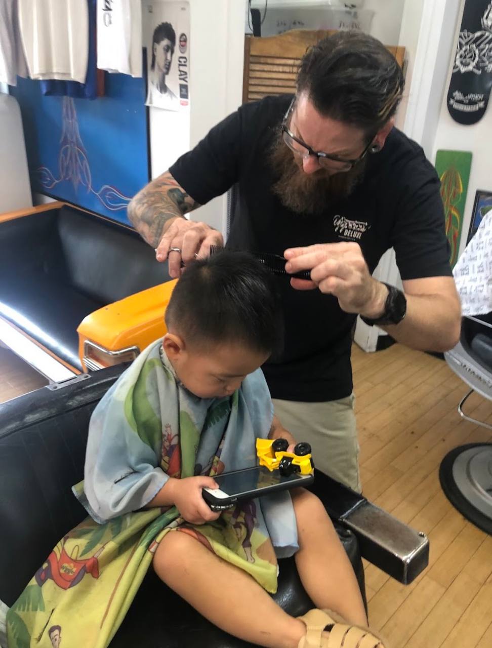 Barber giving a little one their first haircut at Tims Classic Cuts